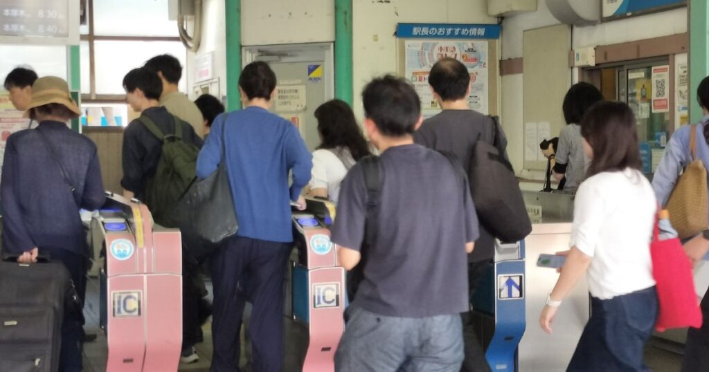 朝の通勤場面。次々と改札を通っていく人々。