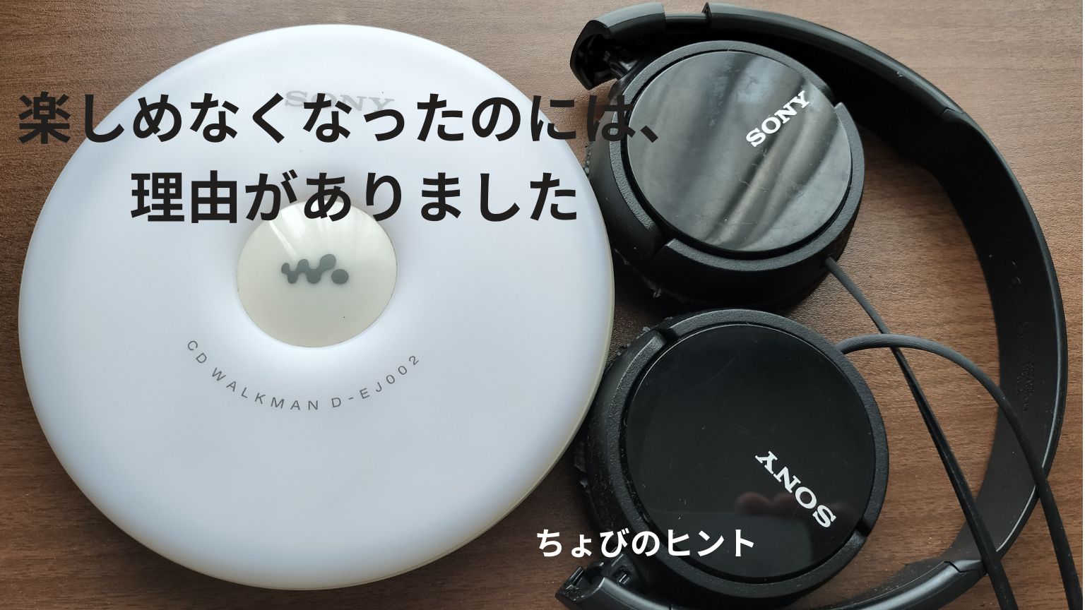 茶色い木目のテーブルの上に白いCDウォークマンと黒いヘッドフォン